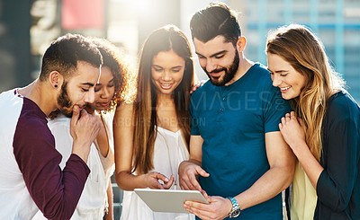 Buy stock photo Shot of young friends using a tablet outside