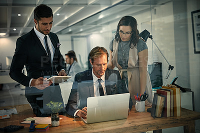 Buy stock photo Shot of a team of colleagues using a laptop together on a night shift at work