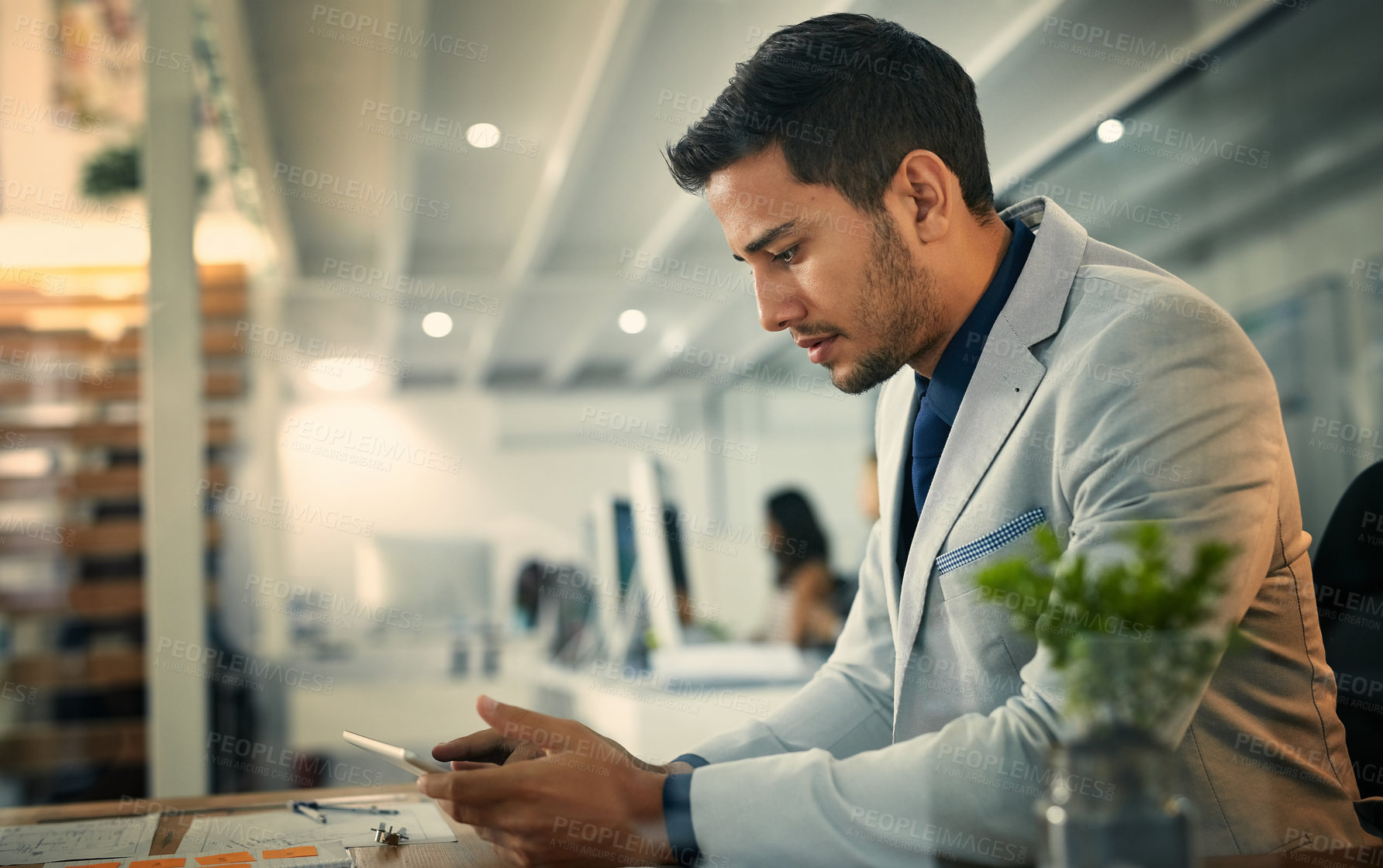 Buy stock photo Shot of a young businessman using a digital tablet in an office