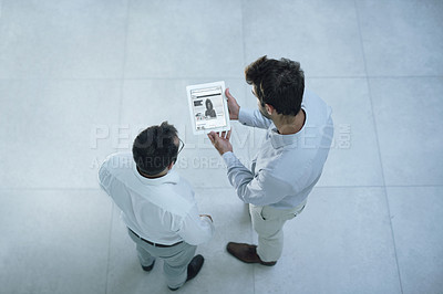 Buy stock photo Shot of two businessmen using a digital tablet in an office