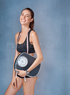 Buy stock photo Studio portrait of a sporty young woman holding a scale against a grey background