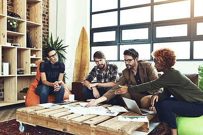 Buy stock photo Shot of a group of young designers discussing paperwork