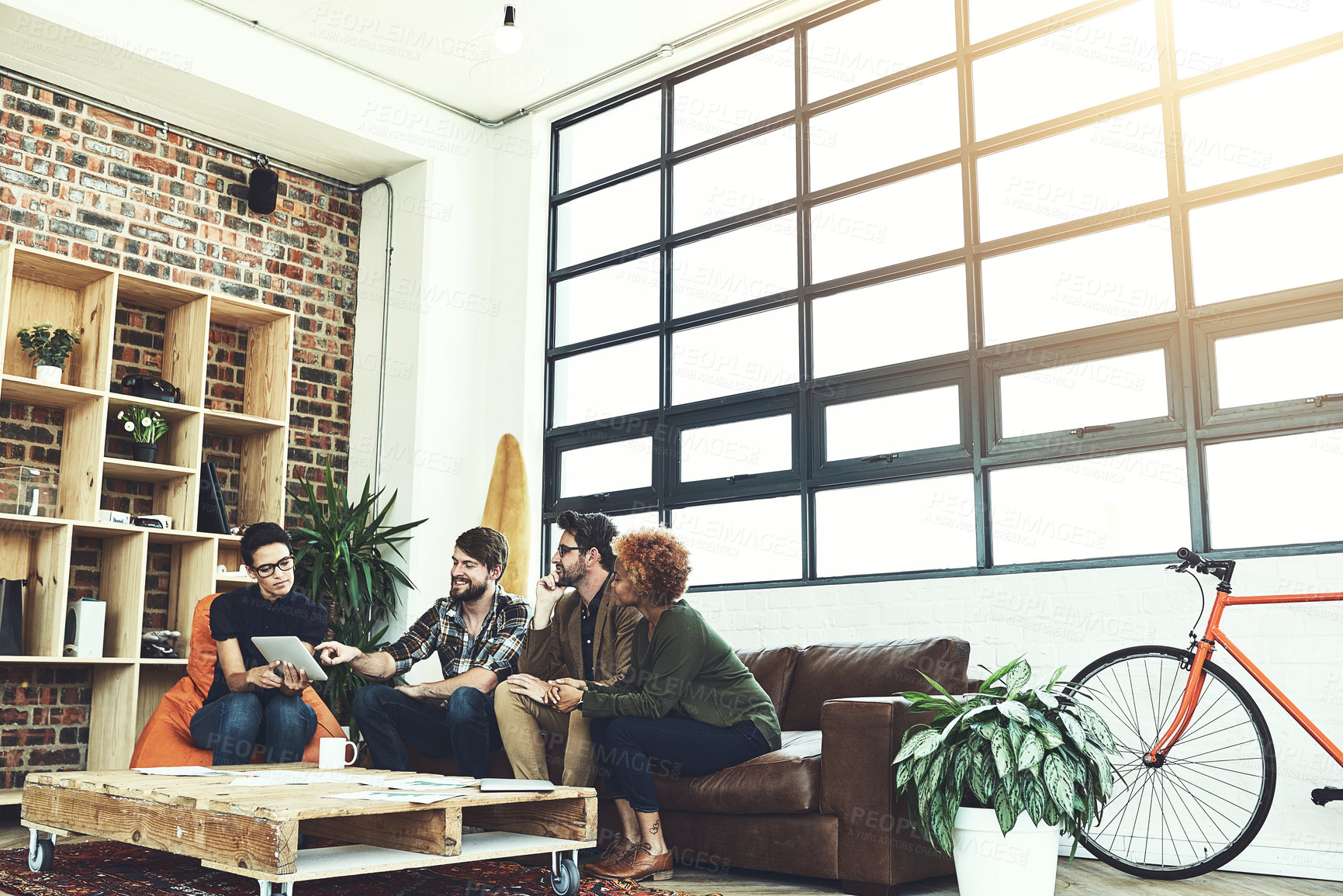 Buy stock photo Shot of a group of designers using a tablet in their brainstorming session