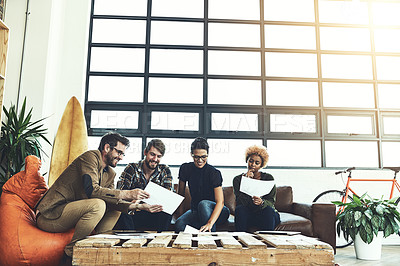 Buy stock photo Shot of a group of young designers discussing paperwork