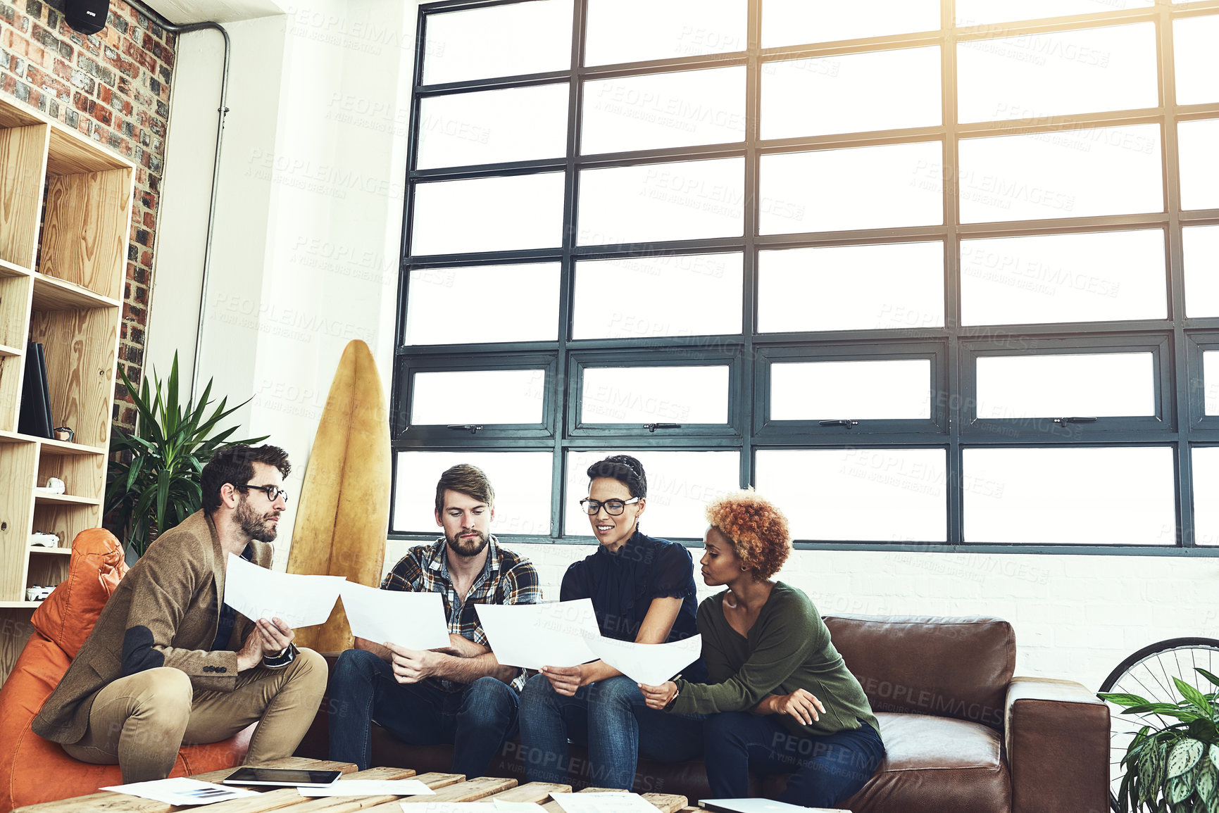 Buy stock photo Shot of a group of young designers discussing paperwork