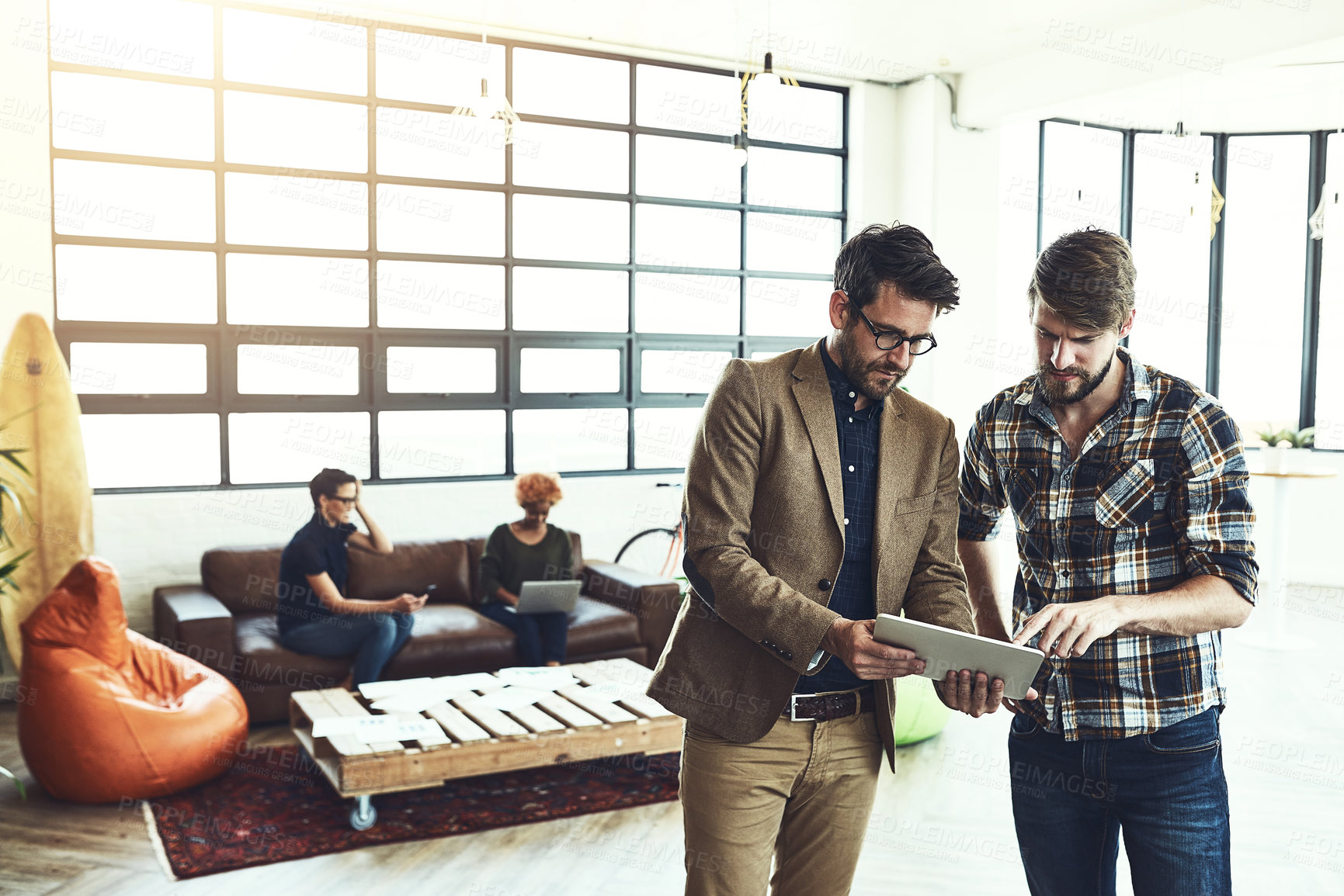 Buy stock photo Shot of two designers discussing something on a tablet