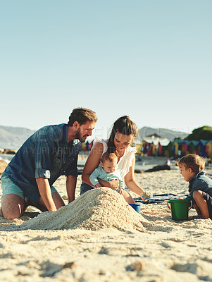 Buy stock photo Shot of a young family spending quality time at the beach