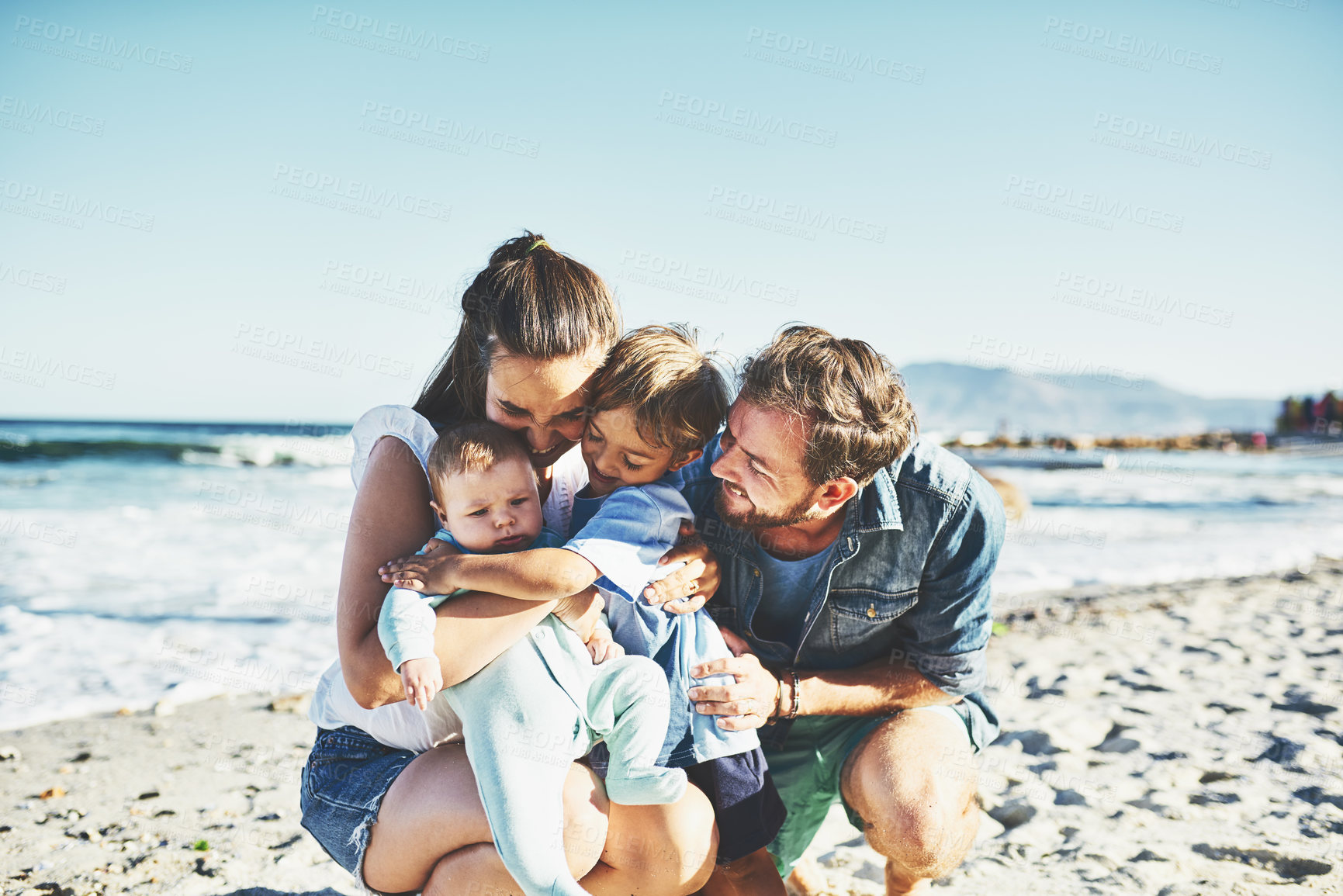 Buy stock photo Shot of a young family spending quality time at the beach