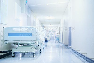 Buy stock photo Shot of a hospital bed in an empty corridor of a modern hospital