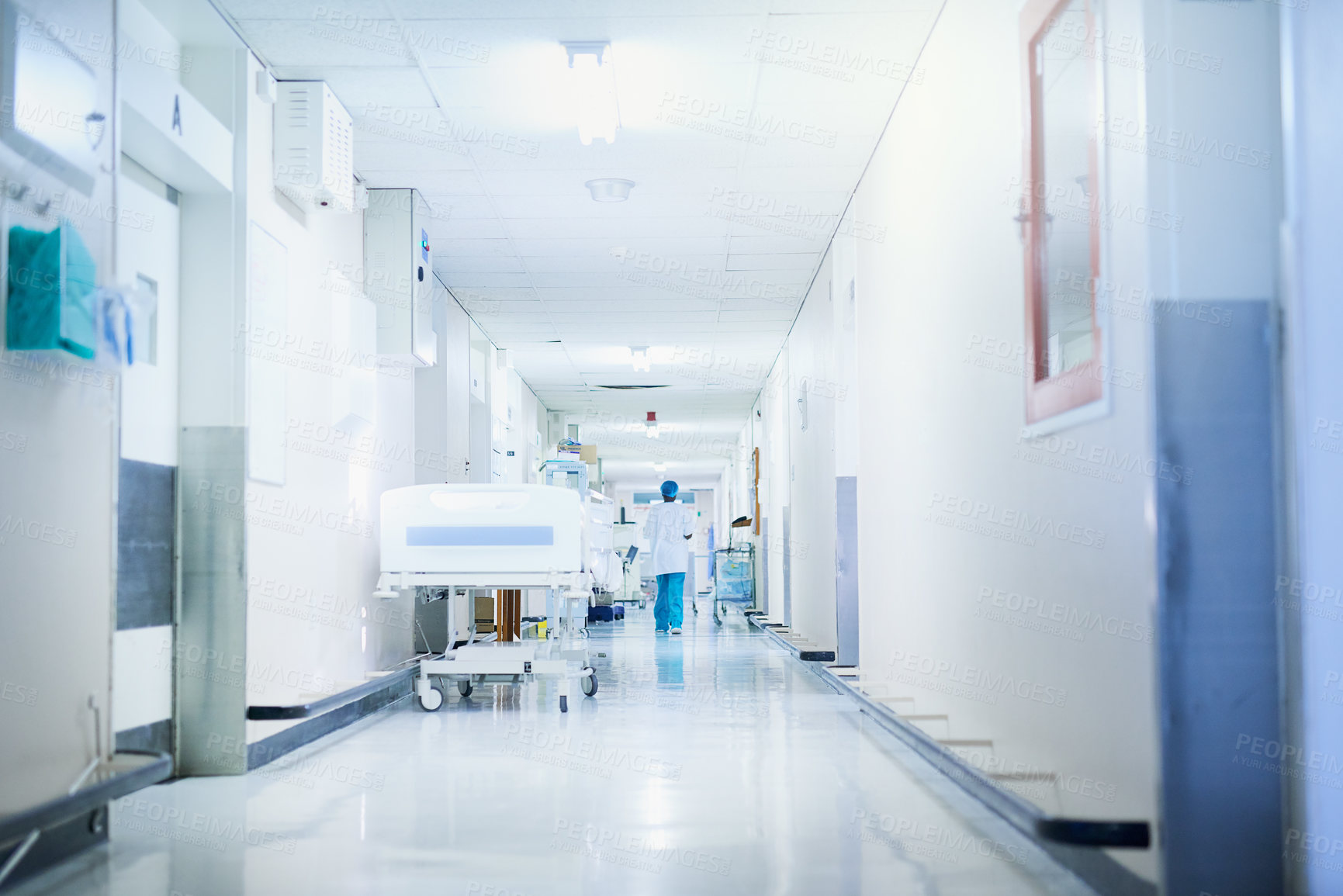 Buy stock photo Rearview shot of a surgeon walking down a hospital corridor