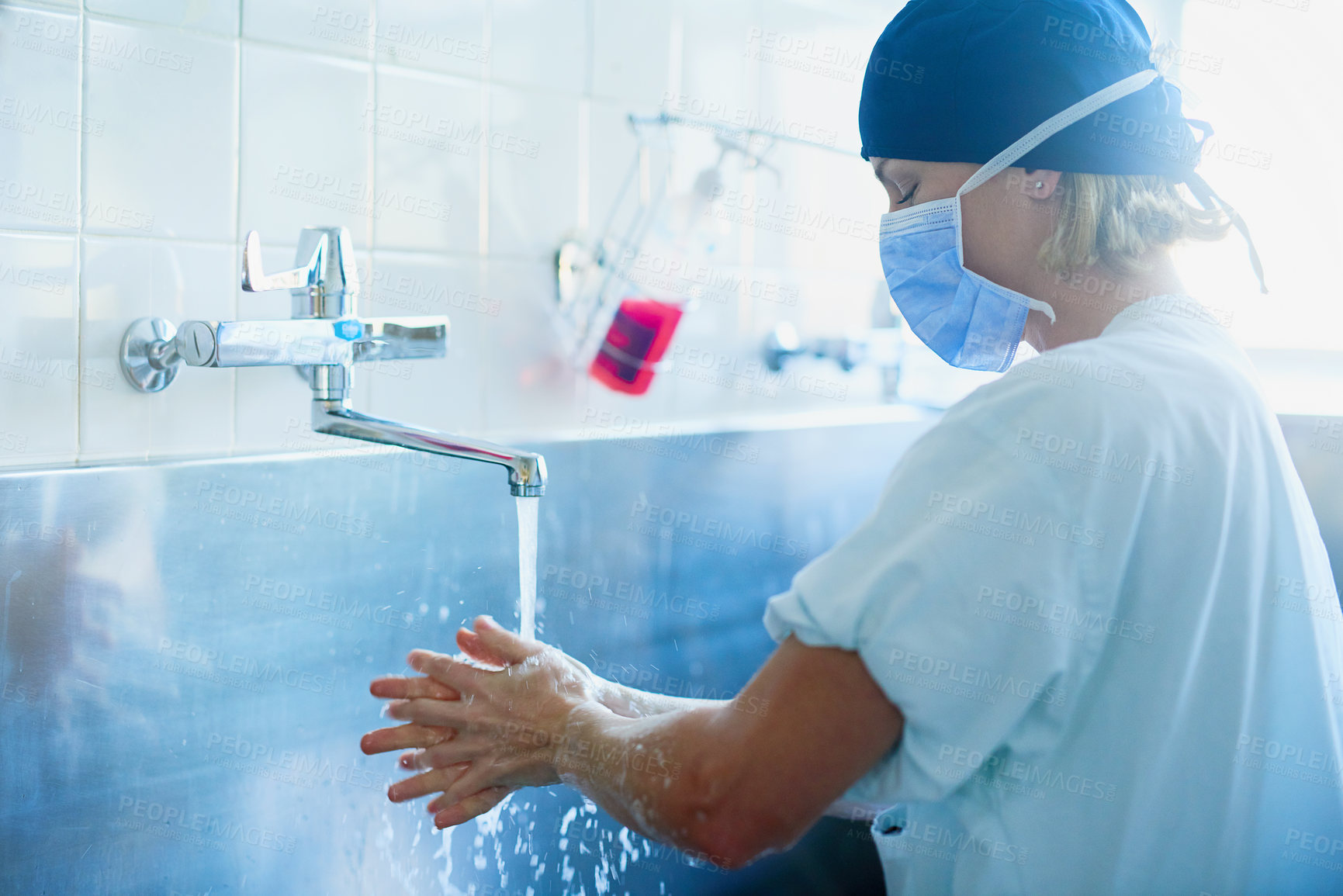 Buy stock photo Shot of a young surgeon sterilizing her hands as part of a surgical routine