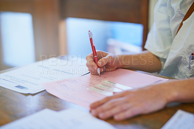 Buy stock photo Cropped shot of a doctor filling out paperwork in a hospital