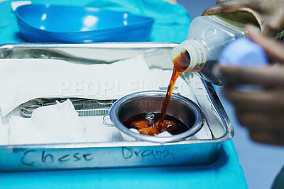 Buy stock photo Cropped shot of a doctor pouring antiseptic into a bowl before a medical procedure