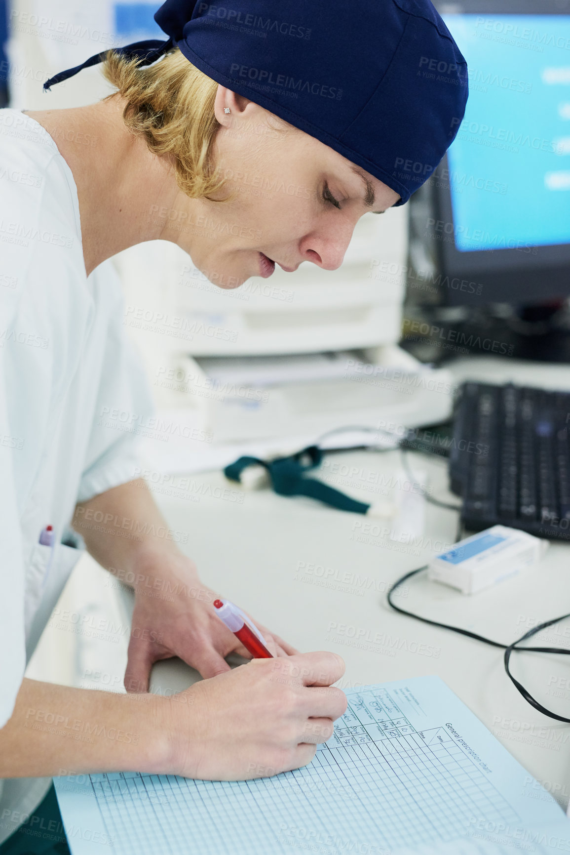 Buy stock photo Shot of a young surgeon filling out paperwork in a hospital