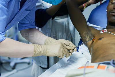 Buy stock photo Cropped shot of a doctor sterilizing a patient’s chest in an emergency room