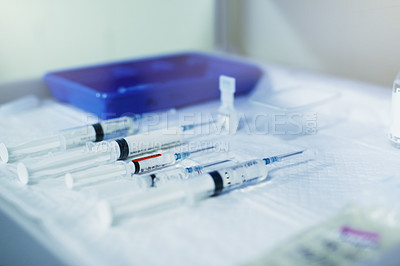 Buy stock photo Shot of a variety of surgical syringes lying on a table