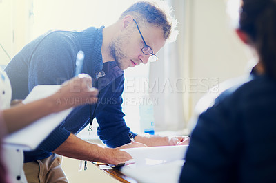 Buy stock photo Shot of a young doctor filling out paperwork in a hospital