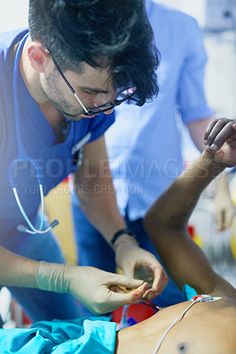 Buy stock photo Shot of a doctor inserting a tube into a patient’s chest in an emergency room