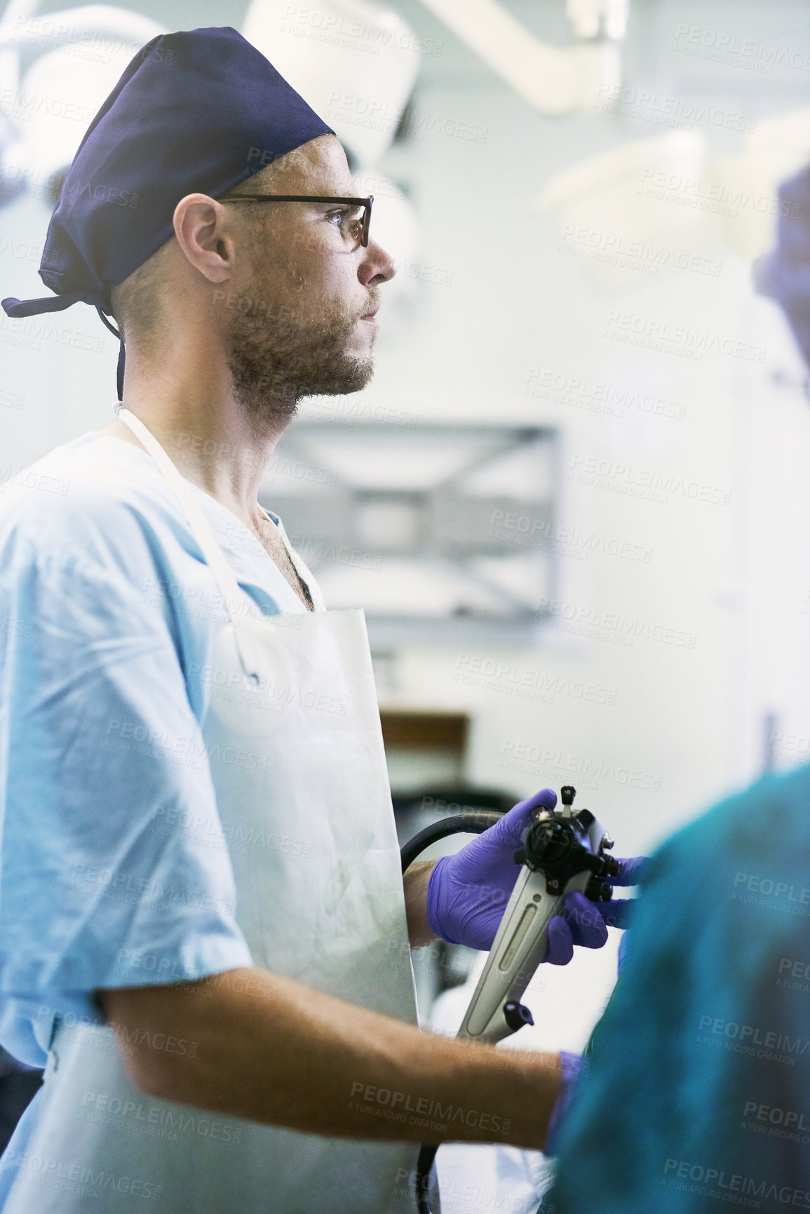 Buy stock photo Shot of a young surgeon performing surgery on a patient in an operating room