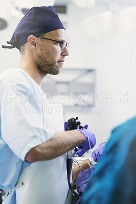 Buy stock photo Shot of a young surgeon performing surgery on a patient in an operating room