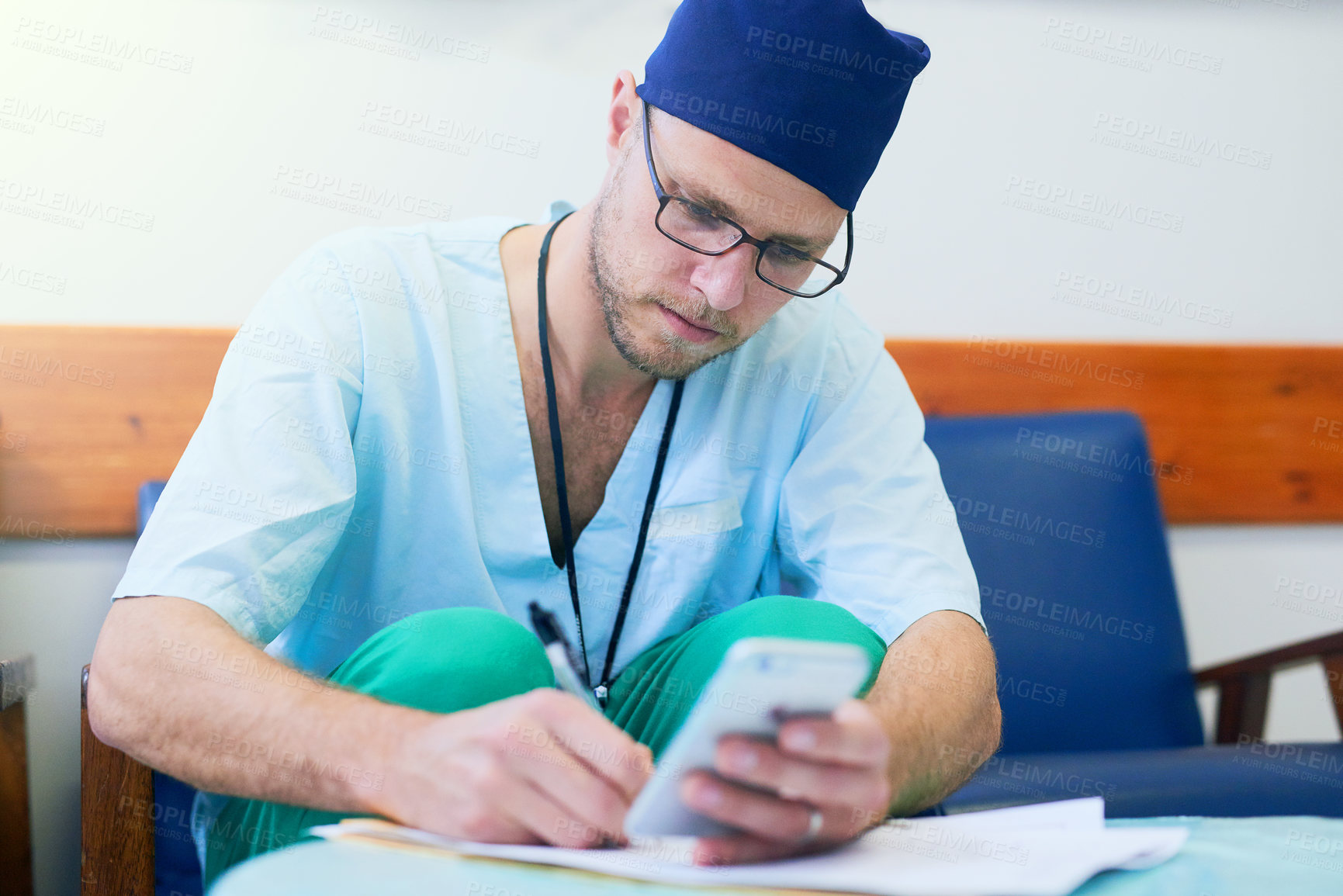 Buy stock photo Shot of a young surgeon filling out paperwork in a hospital