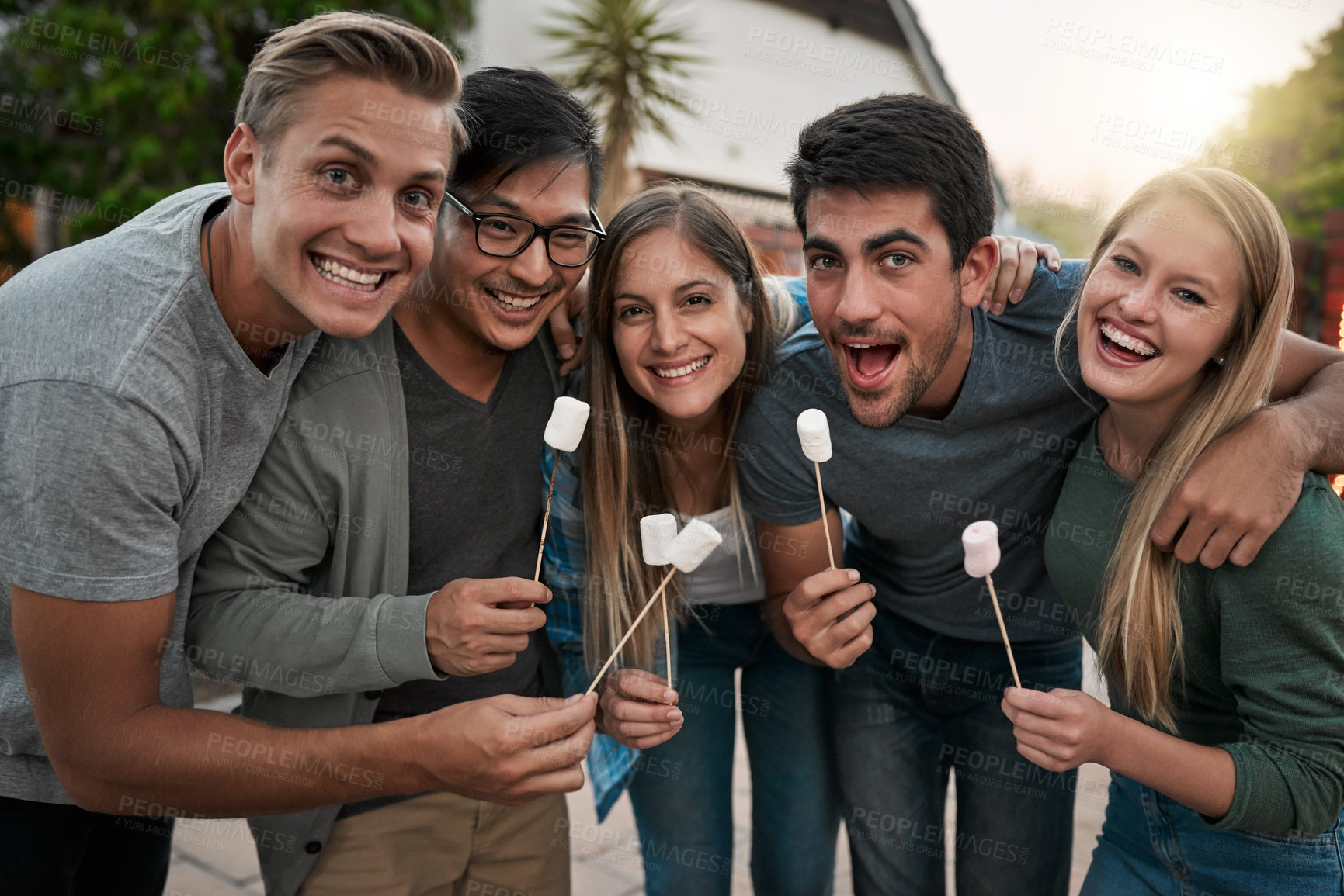 Buy stock photo Portrait of a group of young friends posing together and holding up marshmallows on sticks outside