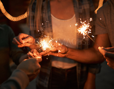 Buy stock photo Shot of a group unrecognizable people's hands holding up sparklers together outside at night