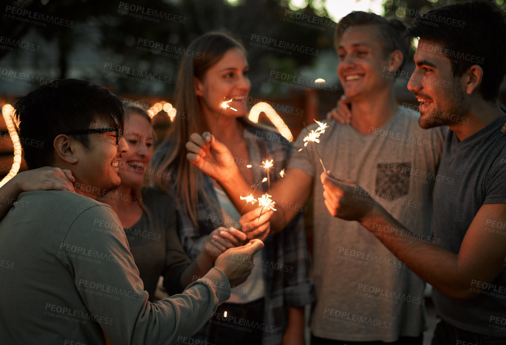 Buy stock photo Happy, group and friends with sparkle outdoor for celebration, care and success of new years party. Smile, people and fireworks with flame glow, achievement and bonding memory at night together