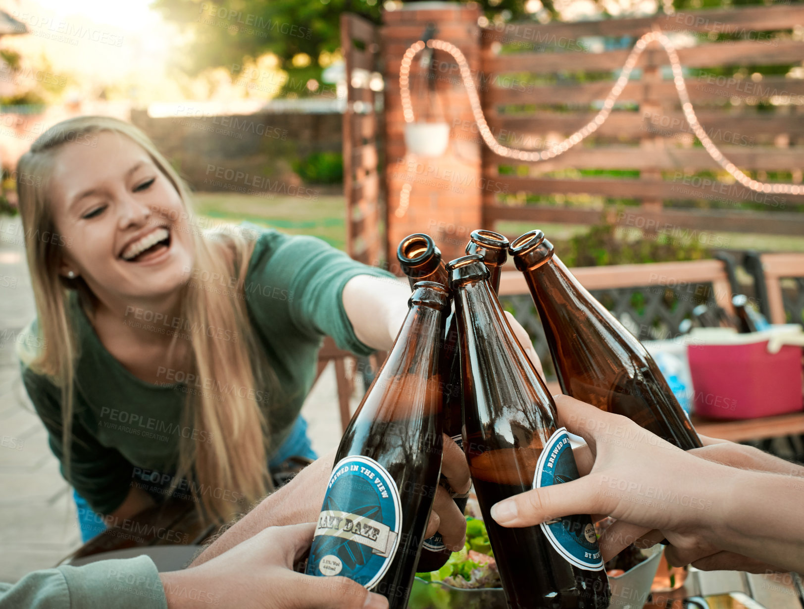 Buy stock photo Shot of a group of young friends holding up drinks and toasting outside around a table to celebrate their friendship