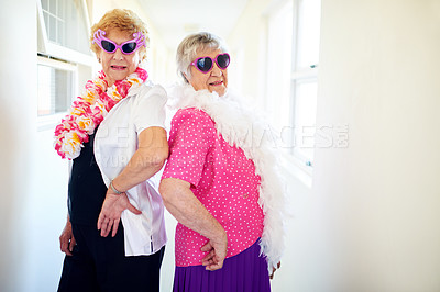 Buy stock photo Shot of two carefree elderly woman wearing sunglasses and posing for the camera inside of a building