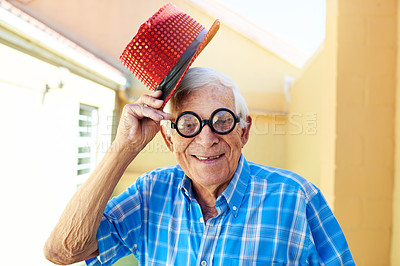 Buy stock photo Shot of a carefree elderly man wearing funky glasses and a hat while posing for the camera inside a building