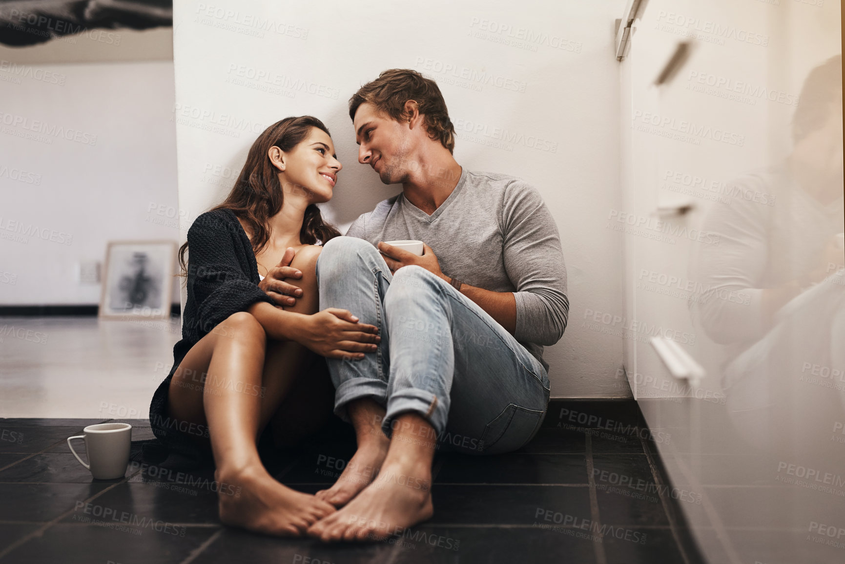 Buy stock photo Shot of an affectionate young couple sitting on the kitchen floor