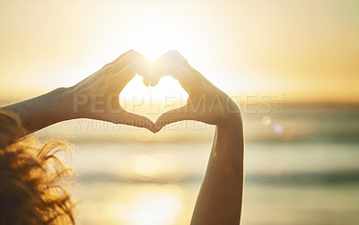 Buy stock photo Closeup shot of an unidentifiable woman forming a heart shape with her hands at the beach