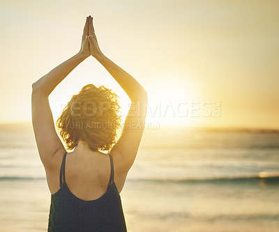 Buy stock photo Rearview shot of a young woman practising yoga at the beach