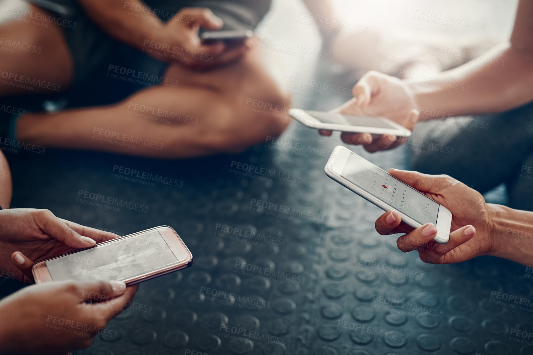 Buy stock photo Closeup shot of a group of people using their cellphones together at the gym