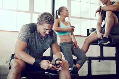 Buy stock photo Shot of a young man texting on his cellphone at the gym