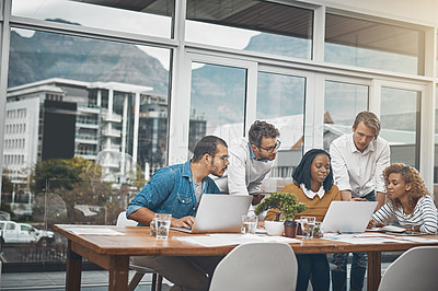 Buy stock photo Shot of a group of businesspeople looking at something on a laptop