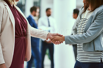Buy stock photo Shot of two unrecognisable businesswomen shaking hands in an office