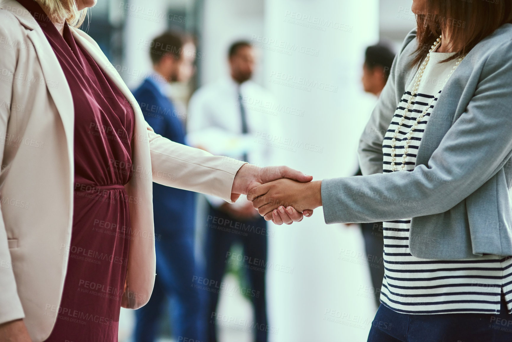 Buy stock photo Shot of two unrecognisable businesswomen shaking hands in an office