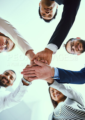 Buy stock photo Low angle shot of a diverse group of businesspeople joining their hands together in unity