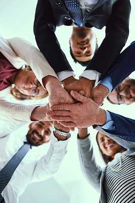 Buy stock photo Low angle shot of a diverse group of businesspeople joining their hands together in unity