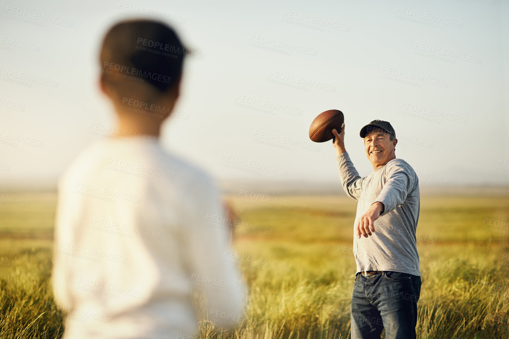 Buy stock photo Kid, dad and football with throw in nature for outdoor sports, teaching and child development. Countryside, man and son on grass field with practice, exercise and bonding on fathers day in Dallas