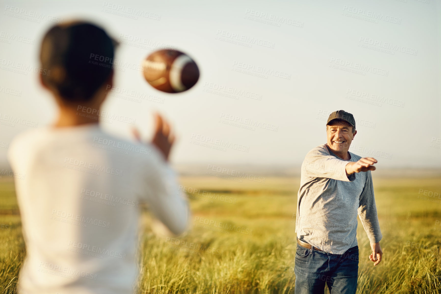 Buy stock photo Shot of father and son playing football on an open field