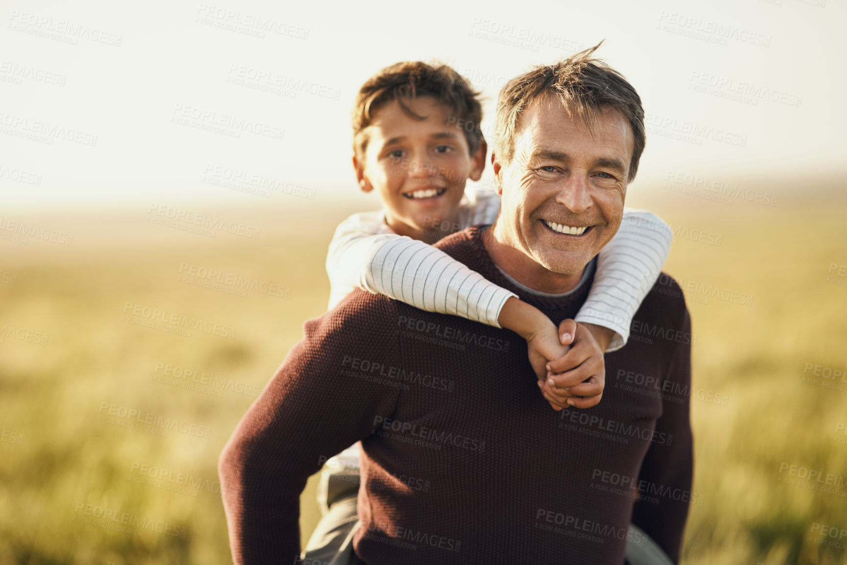 Buy stock photo Shot of a mature man carrying his son on his back