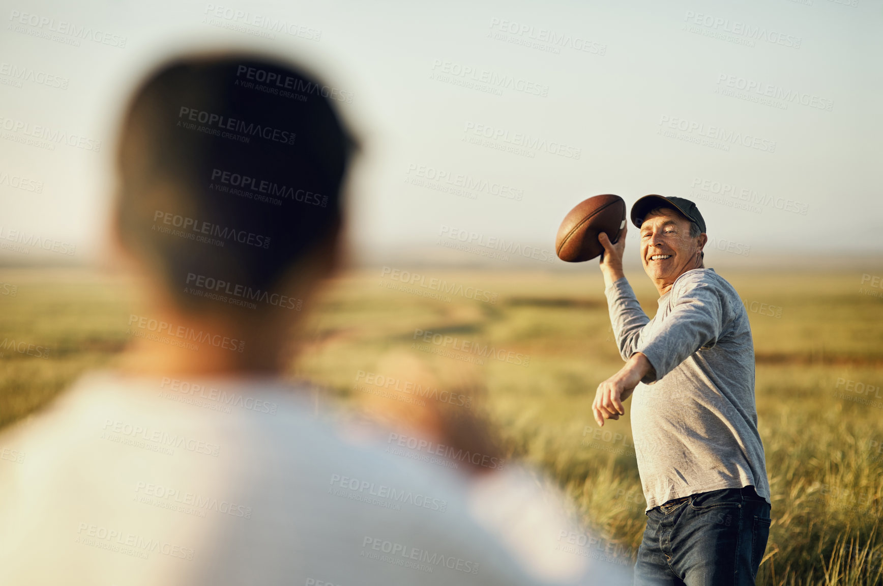 Buy stock photo Son, dad and football with teaching in nature for outdoor sports, child development and exercise together. Happy, man and throw with kid on grass field for bonding, practice and fathers day in Texas