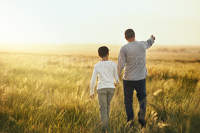 Buy stock photo Shot of a man taking his son for a walk out on an open field
