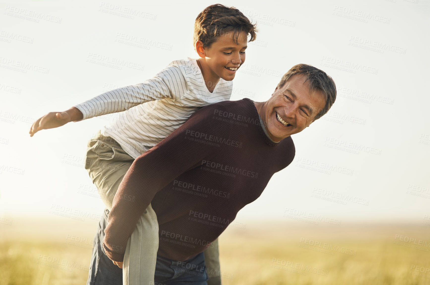 Buy stock photo Shot of a father and son having a good time as the father piggybacks his son