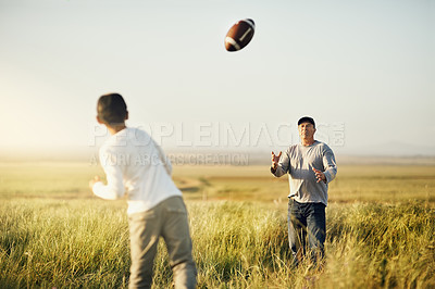 Buy stock photo Shot of father and son playing football on an open field