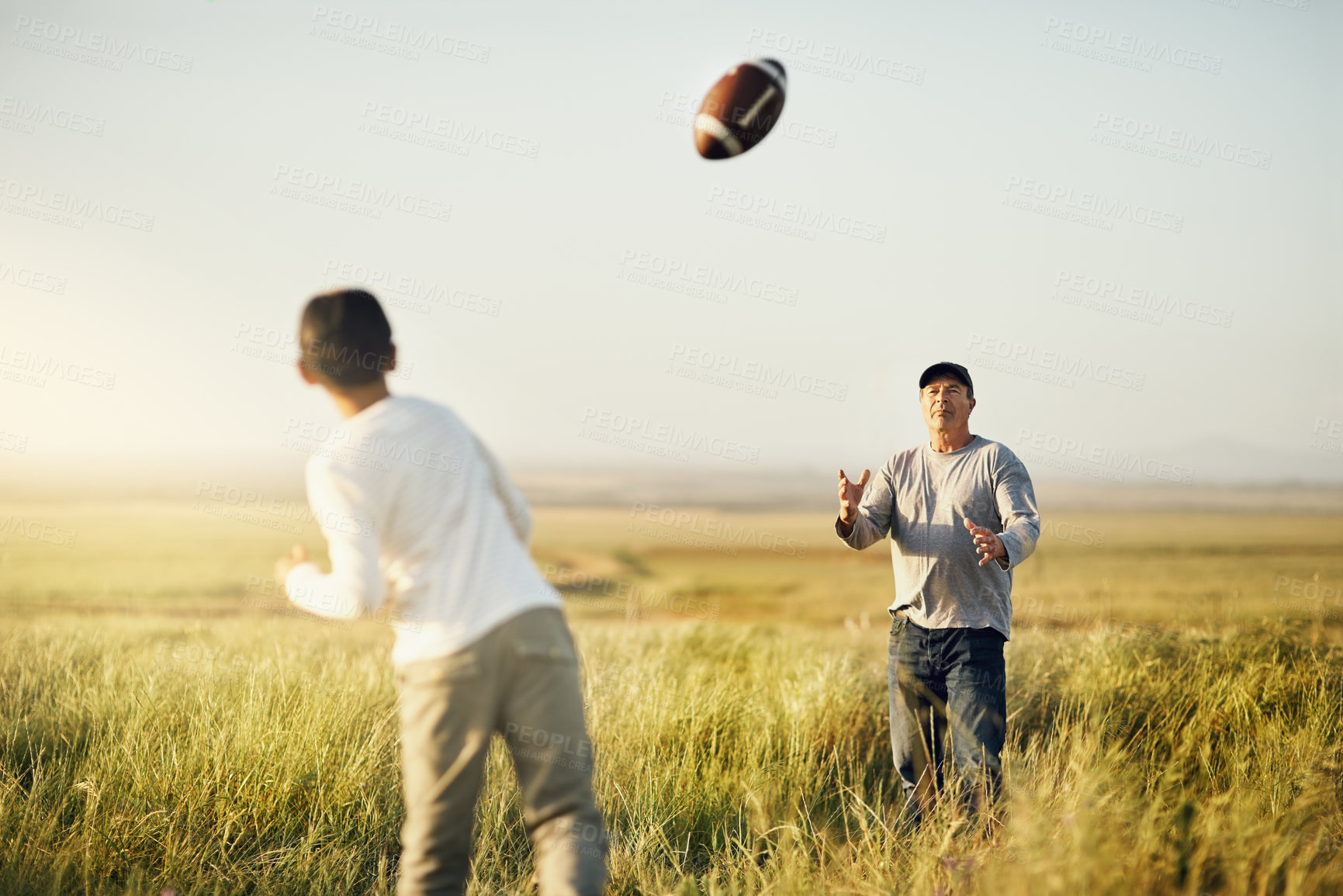 Buy stock photo Shot of father and son playing football on an open field