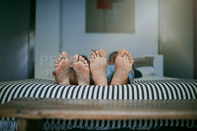Buy stock photo Closeup shot of a young couple lying barefoot in bed